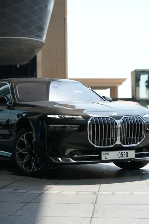 A black BMW 7 Series at a building's entrance, close up