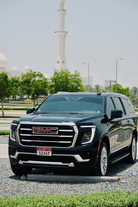 A black GMC Yukon on a driveway beside palm trees