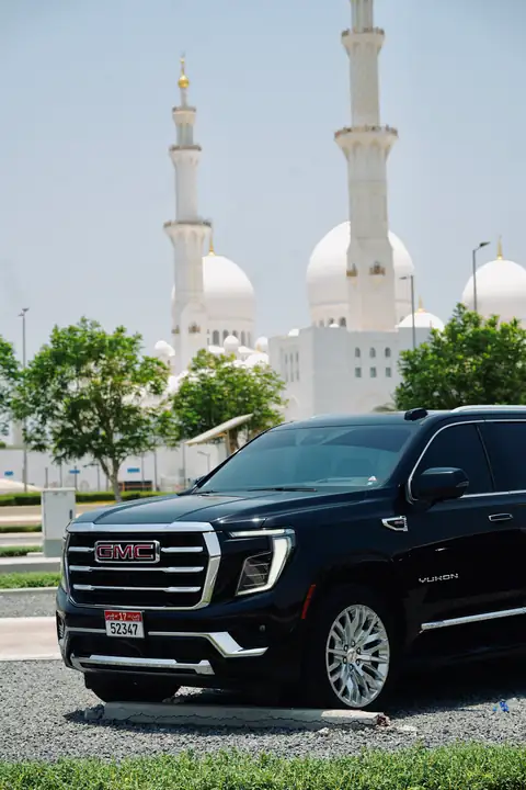 A black GMC Yukon with the Sheikh Zayed Grand Mosque behind