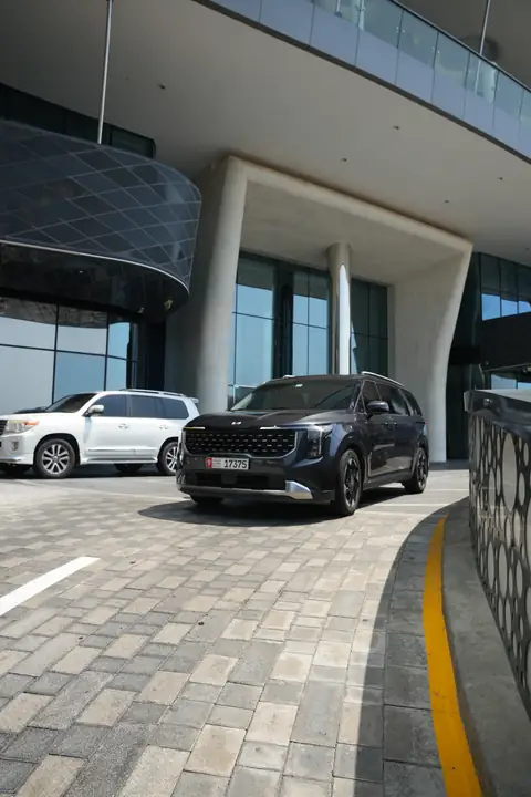 A black Kia Carnival at a building's entrance