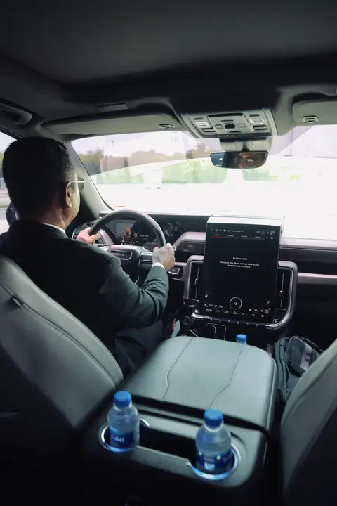 A chauffeur at the wheel of an SUV, seen from the back seat