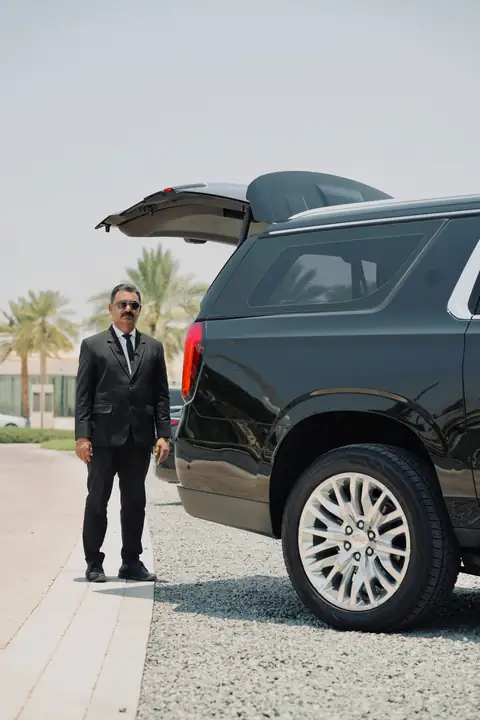 A chauffeur beside the open tailgate of a black SUV