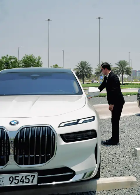 A chauffeur closing the door of a white BMW 7 Series