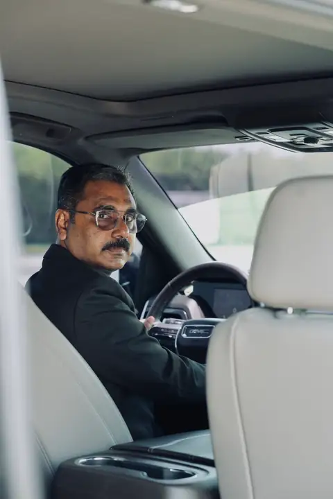 A chauffeur looking back from the driving seat