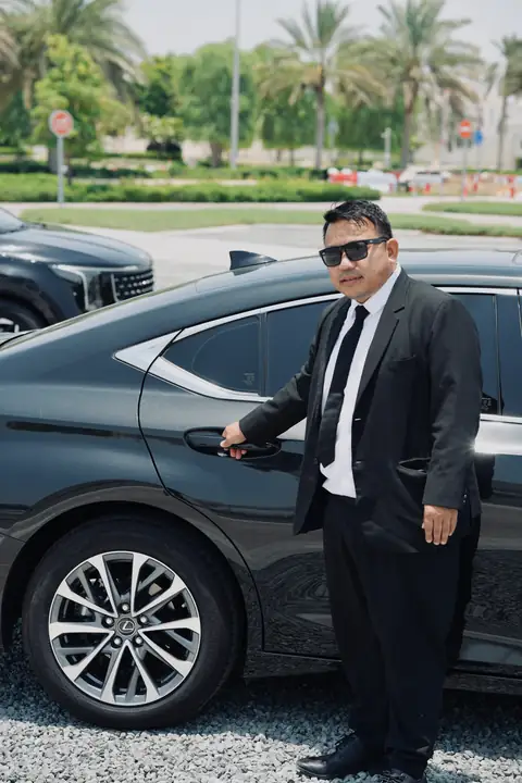 A chauffeur opening the rear door of a black Lexus