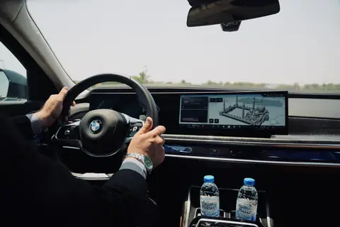 A chauffeur's hand on the wheel of a BMW 7 Series, the road ahead