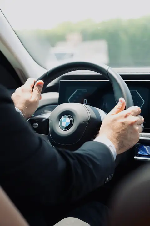 A chauffeur's hands on the wheel of a BMW