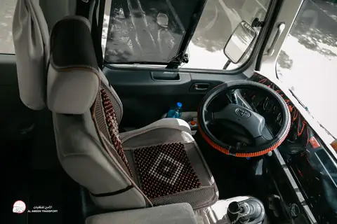 A minibus driving seat with a beaded cover, seen from the passenger side