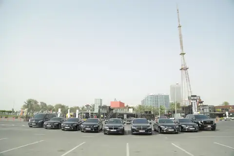 A row of black chauffeur cars with a lattice tower behind