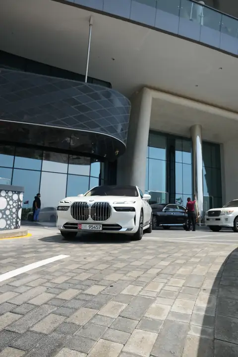 A white BMW 7 Series at a building's entrance