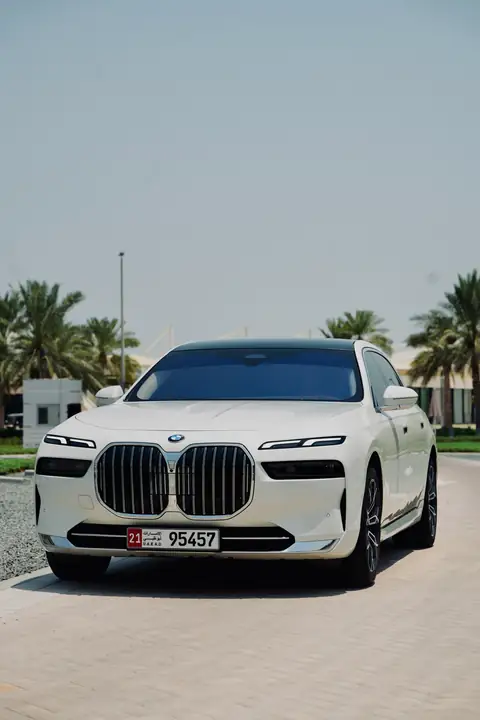 A white BMW 7 Series head-on beside a lawn