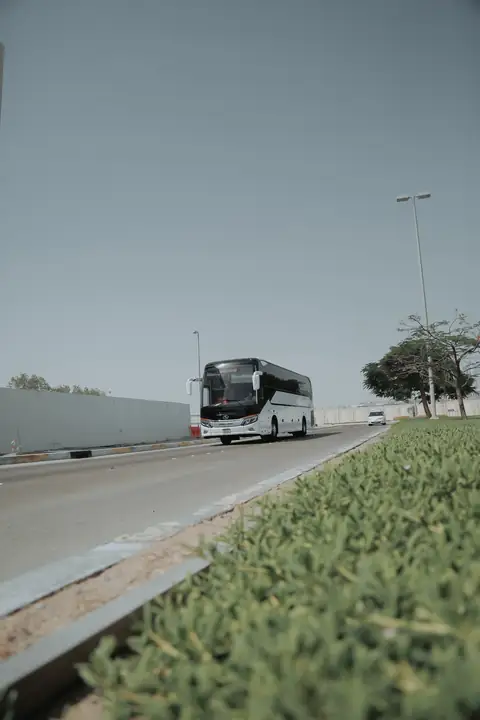 A white coach on a motorway beside a green verge