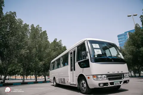 A white Fuso minibus head-on with trees on either side
