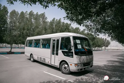 A white minibus from the front quarter in a tree-lined car park