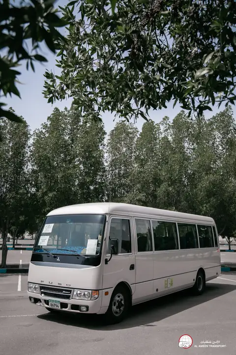 A white minibus from the front quarter with trees behind