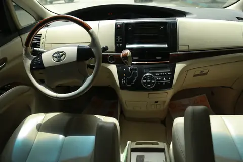 An MPV's front cabin: wood-trim wheel, cream leather and the centre console