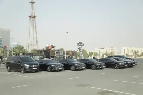 Black chauffeur cars parked in a row with towers behind