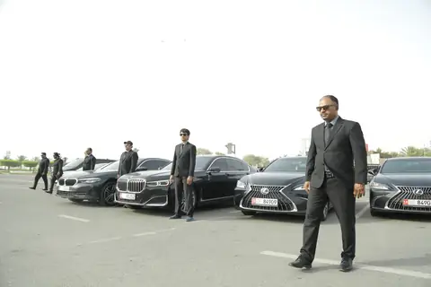 Chauffeurs beside black sedans, one in the foreground
