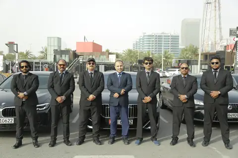 Chauffeurs in a line beside black BMW sedans