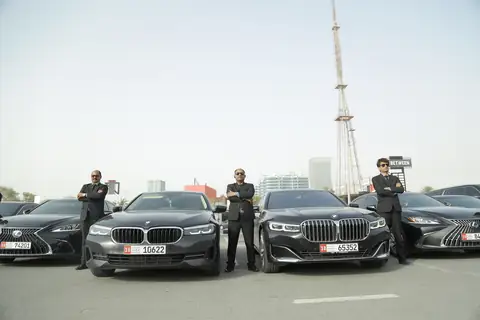 Chauffeurs in dark suits standing beside a row of black cars