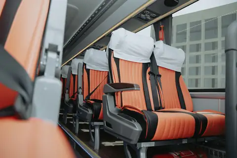 Coach seats in orange leather with white headrest covers, seen from the aisle