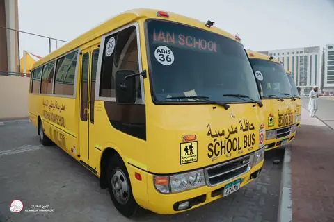 Front quarter view of a yellow school minibus at the school gate