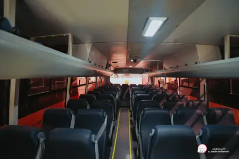 Inside a coach: rows of dark seats under a red-lit ceiling