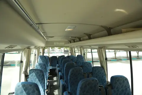 Inside a minibus: blue patterned seats and curtained windows