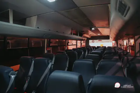 Rows of dark seats inside a coach, the ceiling lit in warm red
