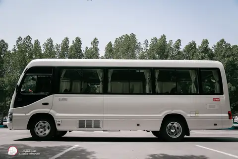Side view of a white minibus in dappled shade