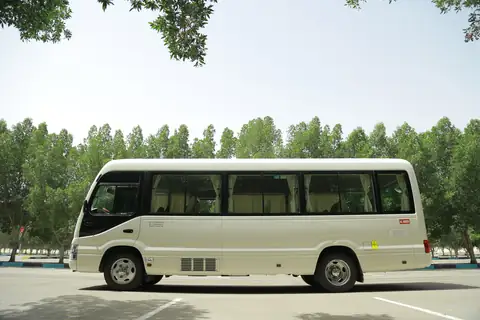 Side view of a white minibus with trees behind