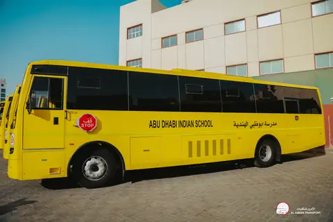 Side view of a yellow school bus lettered Abu Dhabi Indian School