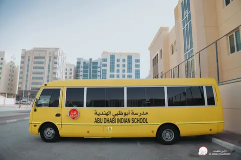 Side view of a yellow school minibus with the city's towers behind