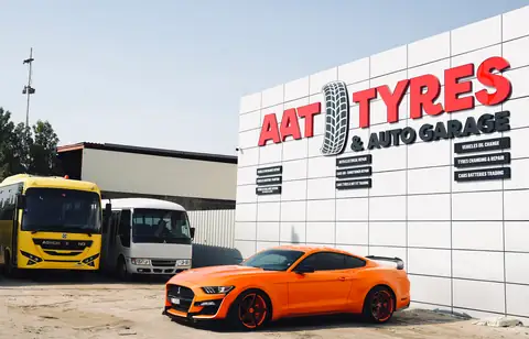 The AAT Tyres & Auto Garage building under its sign, with buses and a car outside