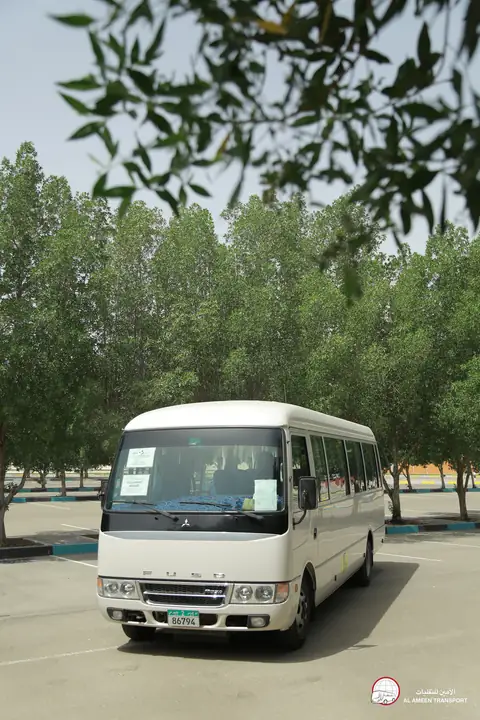 The front of a white minibus under trees