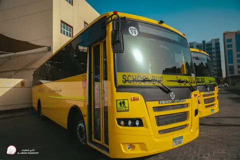 The front of a yellow school bus in Abu Dhabi Indian School livery, close up