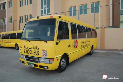 The front of a yellow school minibus with the school's name in Arabic and English