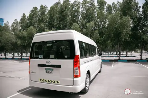 The rear of a white Toyota van with hazard stripes on its bumper