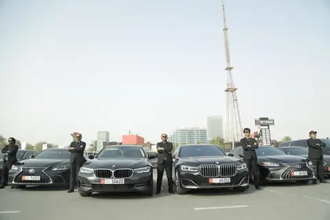 Three chauffeurs beside black BMW sedans