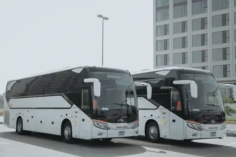 Two white coaches head-on in an open car park