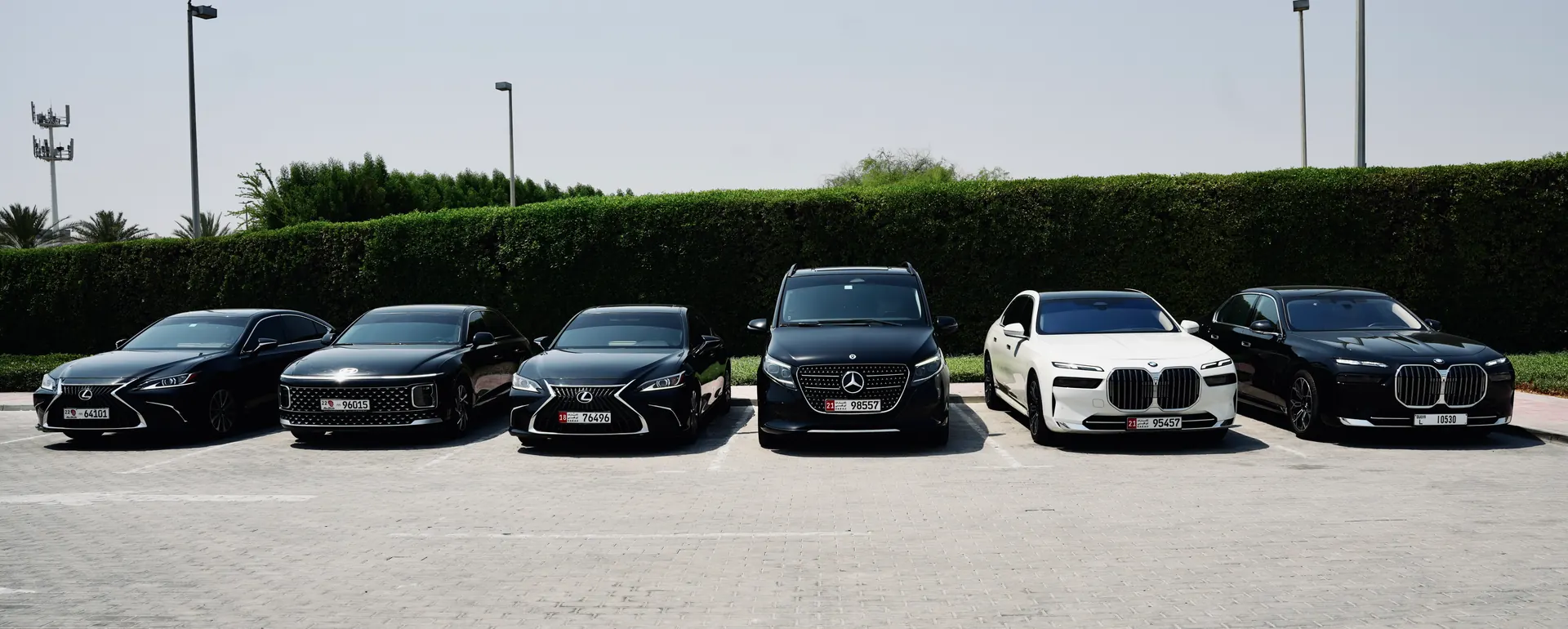 AAT Limousine chauffeur cars lined up on a forecourt — saloons, an SUV and a people carrier, on UAE plates.